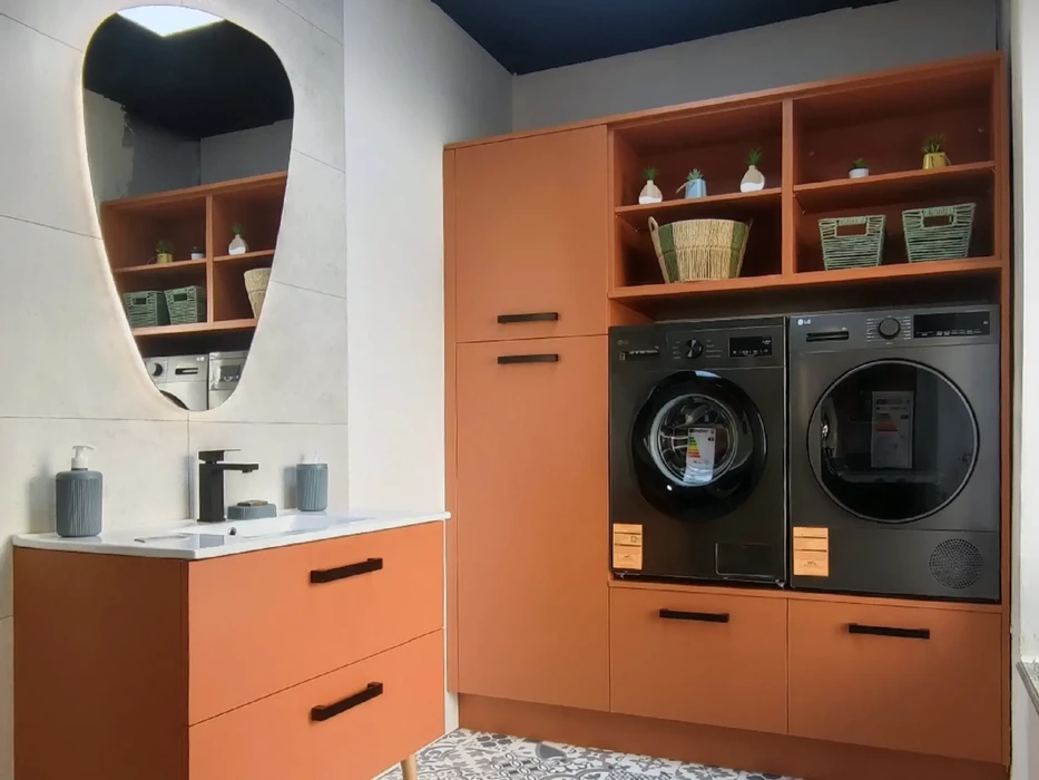 Buanderie moderne avec mobilier orange intégré comprenant lave-linge et sèche-linge LG encastrés, étagères de rangement avec paniers en osier et objets décoratifs