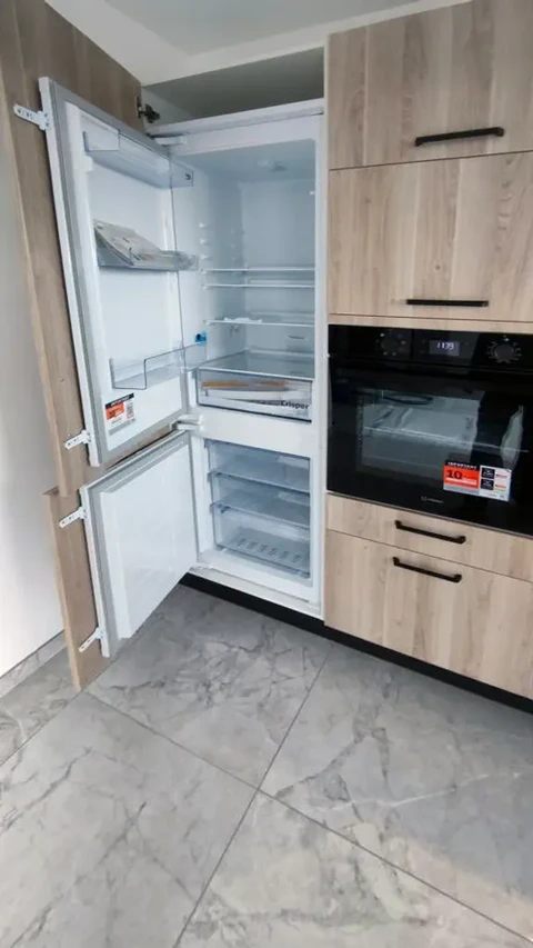 Cuisine moderne avec réfrigérateur-congélateur intégré ouvert révélant compartiments et étagères en verre