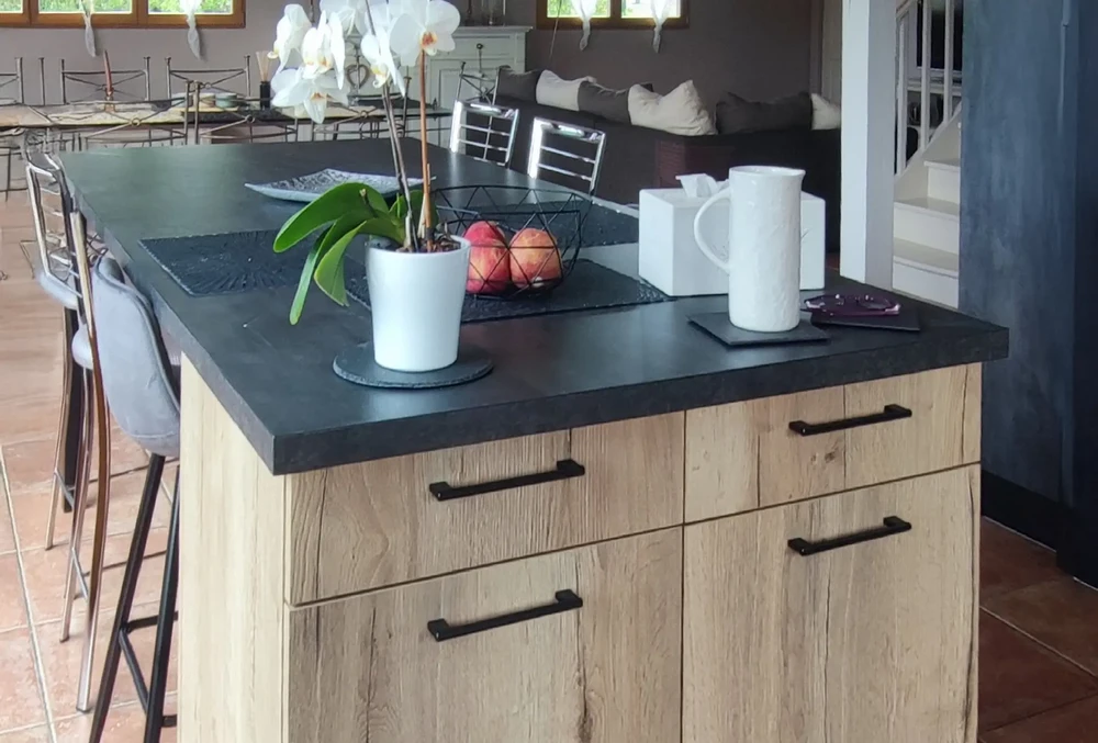 Cuisine moderne avec îlot central en bois clair et plan de travail noir