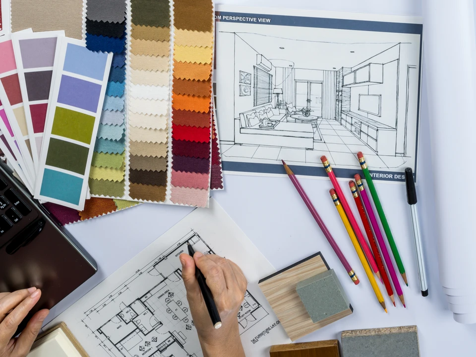 Bureau d'architecte d'intérieur avec designer travaillant sur plans techniques au crayon